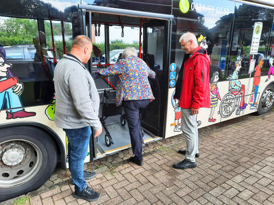 A woman with a walking frame gets on a bus.